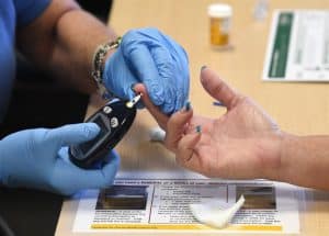 Doctor taking a blood sample to check diabetes mellitus and instruct to prevent it